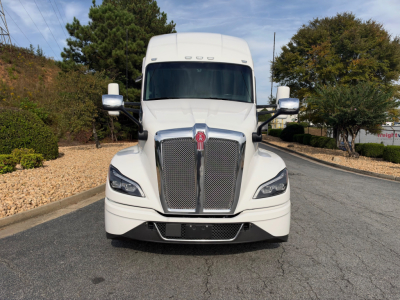 Kenworth T680 front view showing grille badge and headlights in a white sleeper cab truck.