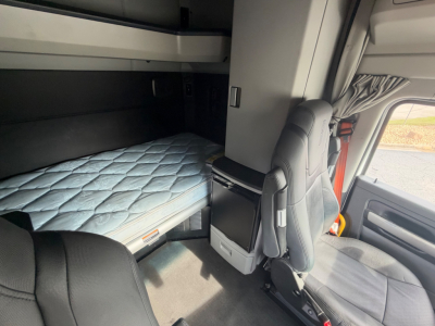 Kenworth T680 sleeper cab interior showing bunk bed area, captain chair, and dashboard area in a used truck.