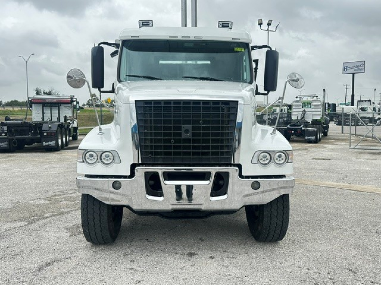 Front view of a white 2020 Volvo VHD roll-off truck with large black grille, dual circular headlights, chrome bumper, and side mirrors