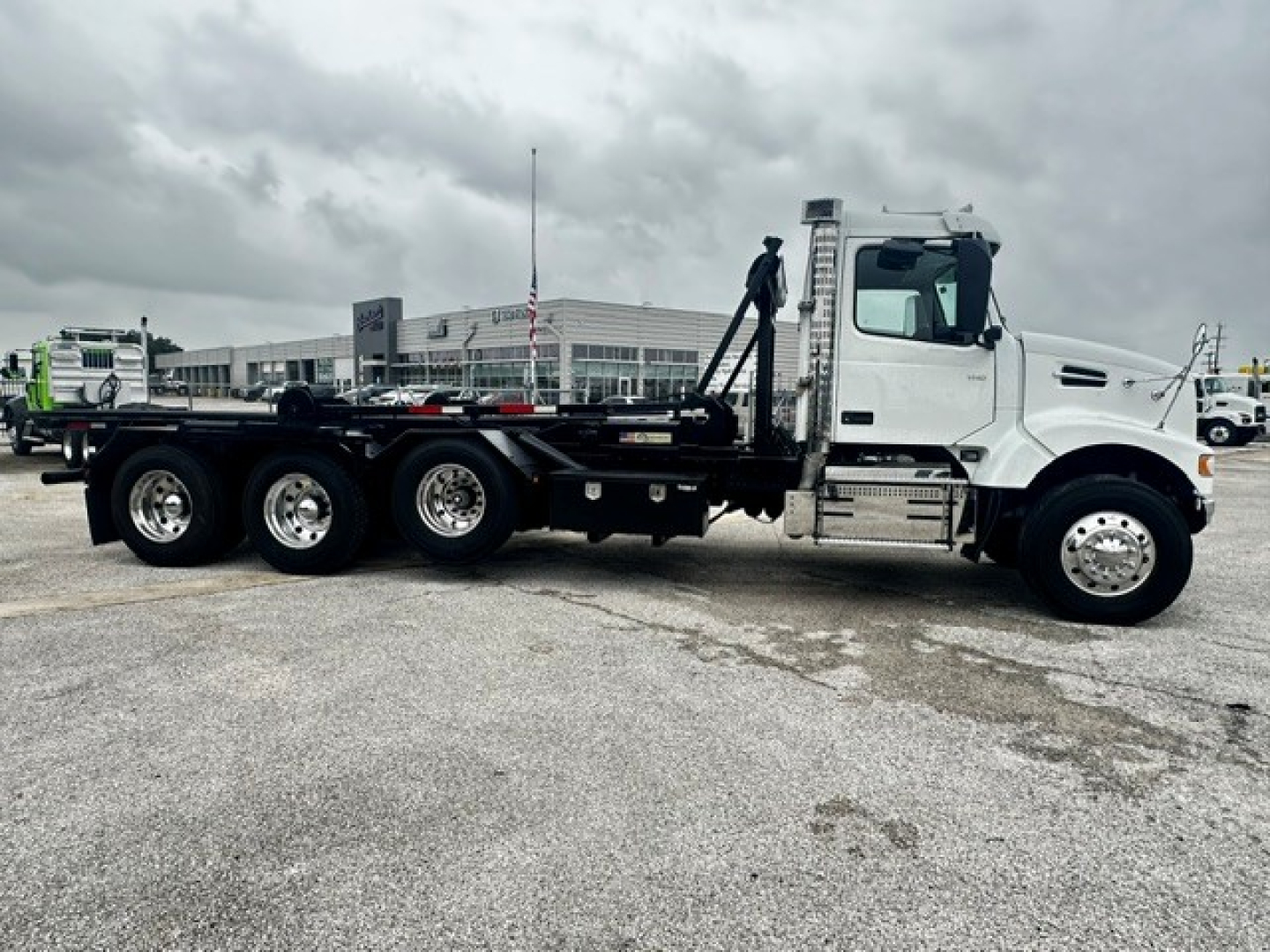 Volvo VHD rollback truck side view showing white cab, long flatbed, and dual rear axles with multiple wheels.