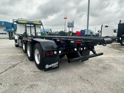 Rear and side view of a 2020 Volvo VHD rolloff truck showing dual rear axles, flatbed, rear bumper with taillights, mud flaps with Buckner tag, and equipment hitch.