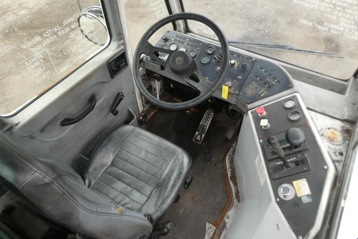 Vehicle cab interior showing steering wheel, dashboard with controls, and driver's seat in a used yard truck.