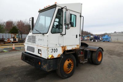 Truck cab showing white Ottawa yard truck with 700 and rusted lower front, front grille, and orange wheels in a storage yard.
