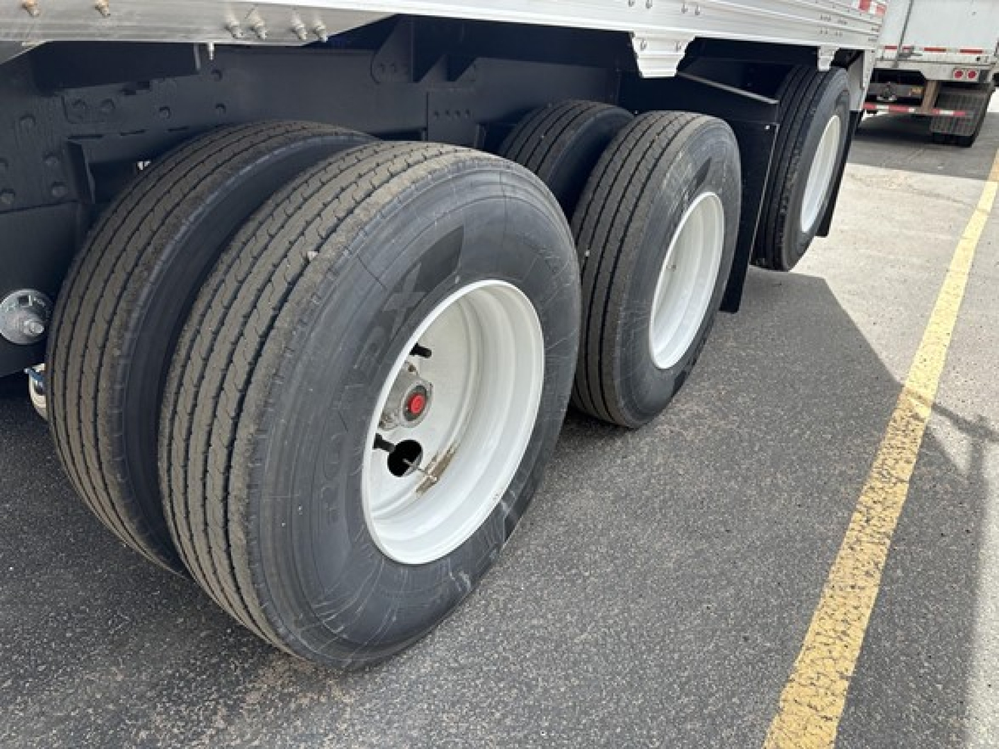 Timpte Super Hopper trailer wheels and tandem axle in-service showing dual rear tires and white rims.