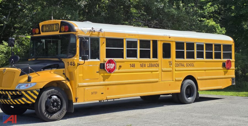 School bus, 2018 International CE 300, yellow, side view with stop sign, warning stripes on bumper, bus number 148, ‘New Lebanon Central School’ text.