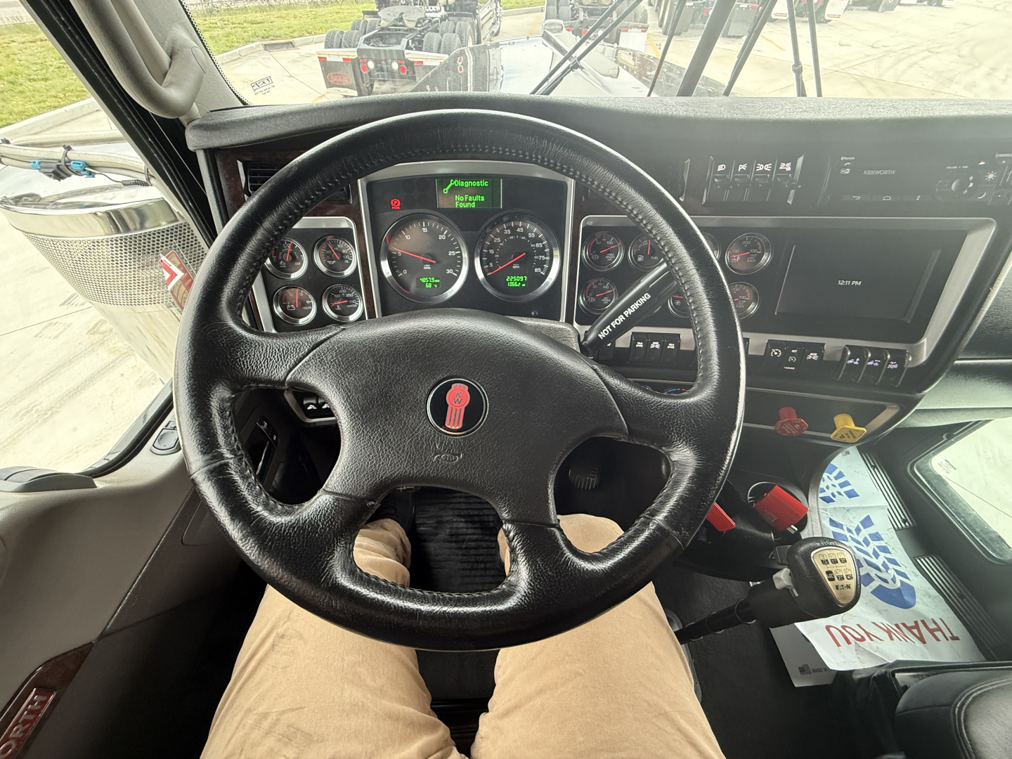 Kenworth W900L cockpit with steering wheel, gauges, and dashboard controls visible.