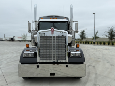 Kenworth W900L front view showing large chrome grille, dual vertical exhaust stacks, rectangular headlights, and chrome bumper.