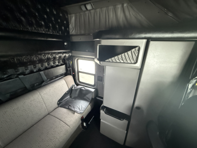 Kenworth W900L sleeper cab interior showing bunk area and storage compartments with grey upholstery.