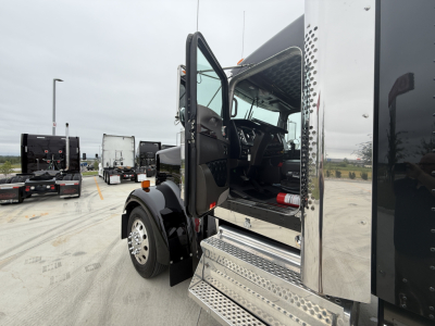 Kenworth W900L conventional sleeper cab with open door showing interior dashboard and chrome steps.