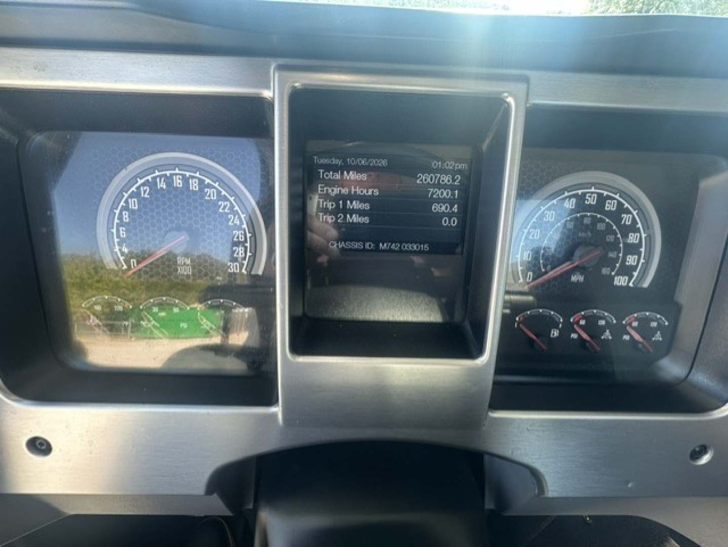 Dashboard of a Mack truck showing gauges and a central digital display with mileage and engine hours.