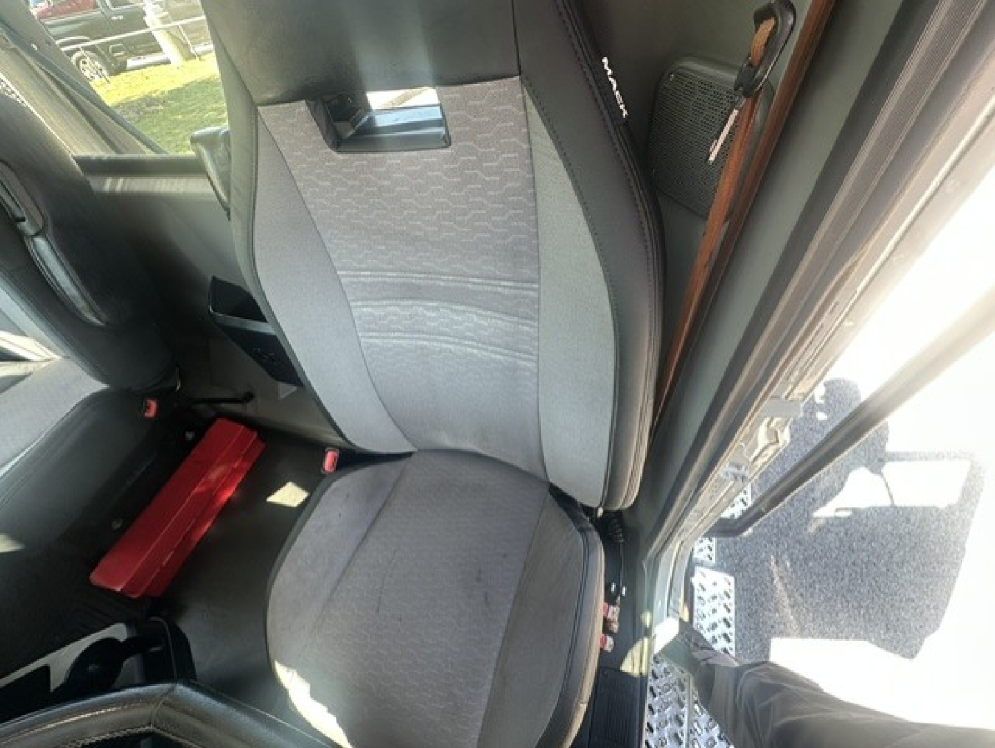 Interior view of a 2023 Mack ANTHEM 64T cab showing driver's seat with fabric upholstery and side steps near door.