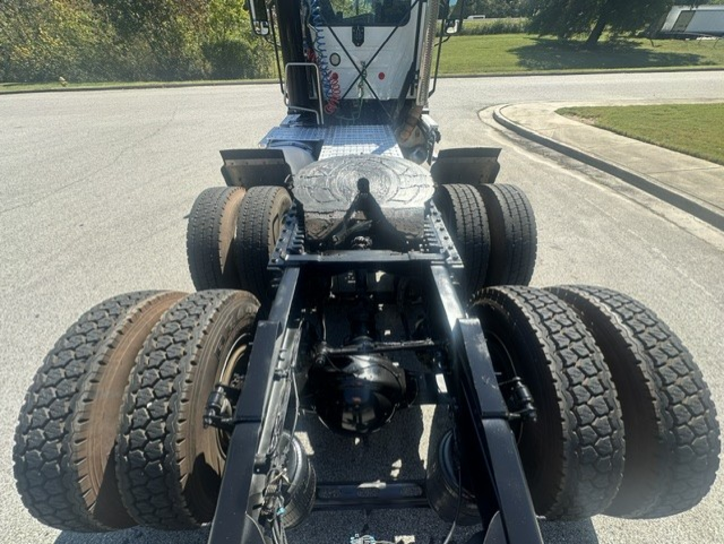 Rear view of a Mack ANTHEM 64T tractor chassis showing dual rear axles, suspension, and fifth wheel mount with tires visible.