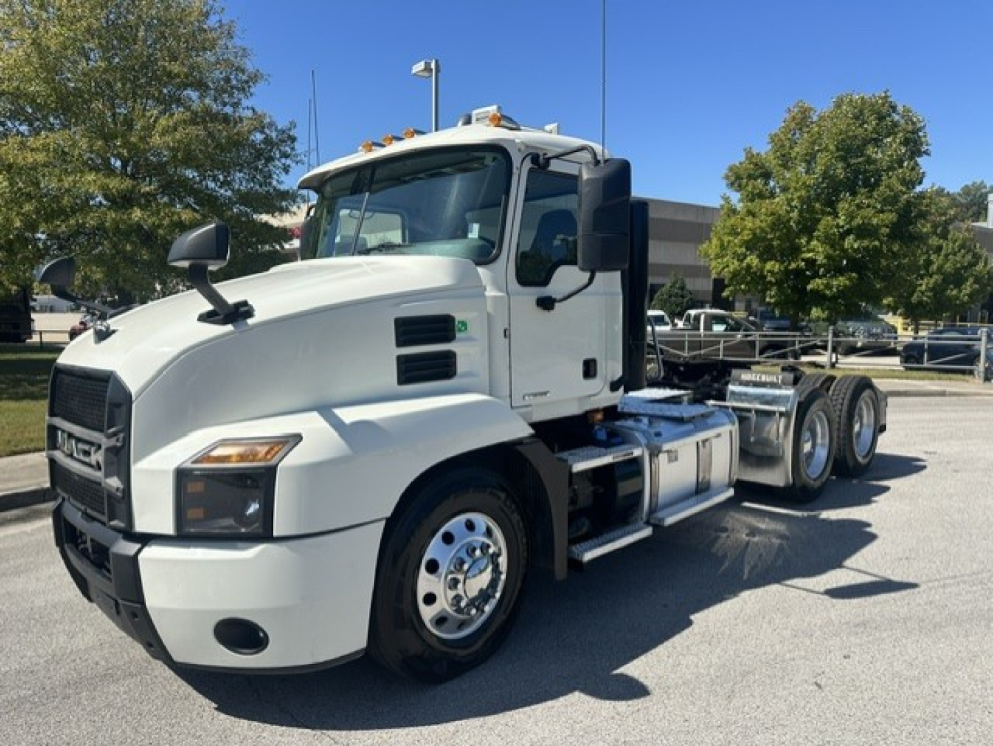 Mack Anthem 64T truck in white, front-left view showing cab, headlights, and dual rear axles.
