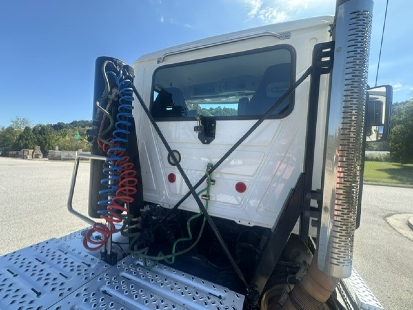 Truck cab back view showing air lines and exhaust stack near vertical surface on diamond-plate platform