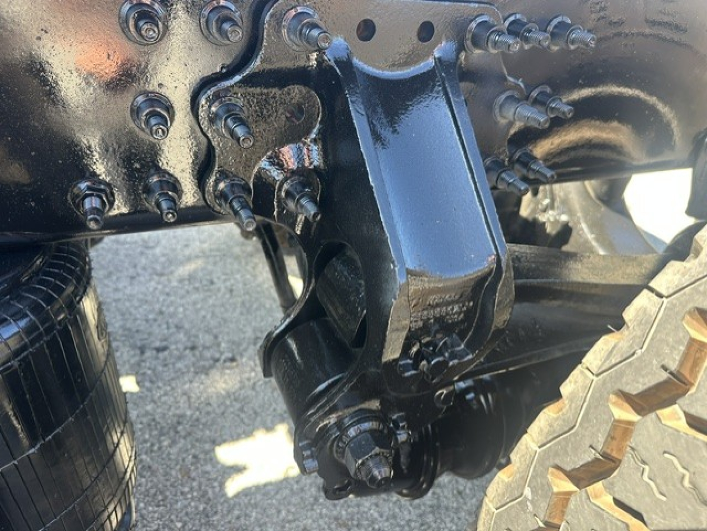 Mack ANTHEM 64T truck undercarriage showing a suspension hitch/auxiliary mounting with bolts and a single tire visible