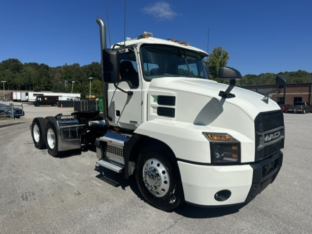 Truck cab with white Mack ANTHEM 64T, front-right angle showing cab, grille, headlights, steps, exhaust stack, and dual rear axles on a sunny day.