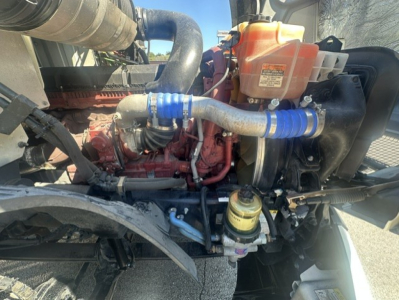 Mack ANTHEM 64T engine bay showing coolant reservoir, hoses with blue clamps, air intake hose, and exposed engine components.