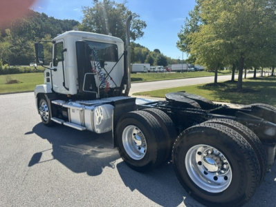 Truck side view of a white 2023 Mack ANTHEM 64T daycab with single sleeper, showing the cab and dual rear axles without trailer.