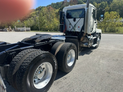 Truck chassis and cab of a used 2023 Mack ANTHEM 64T, rear triple axles, fuel tanks, and cabin visible from a side angle.