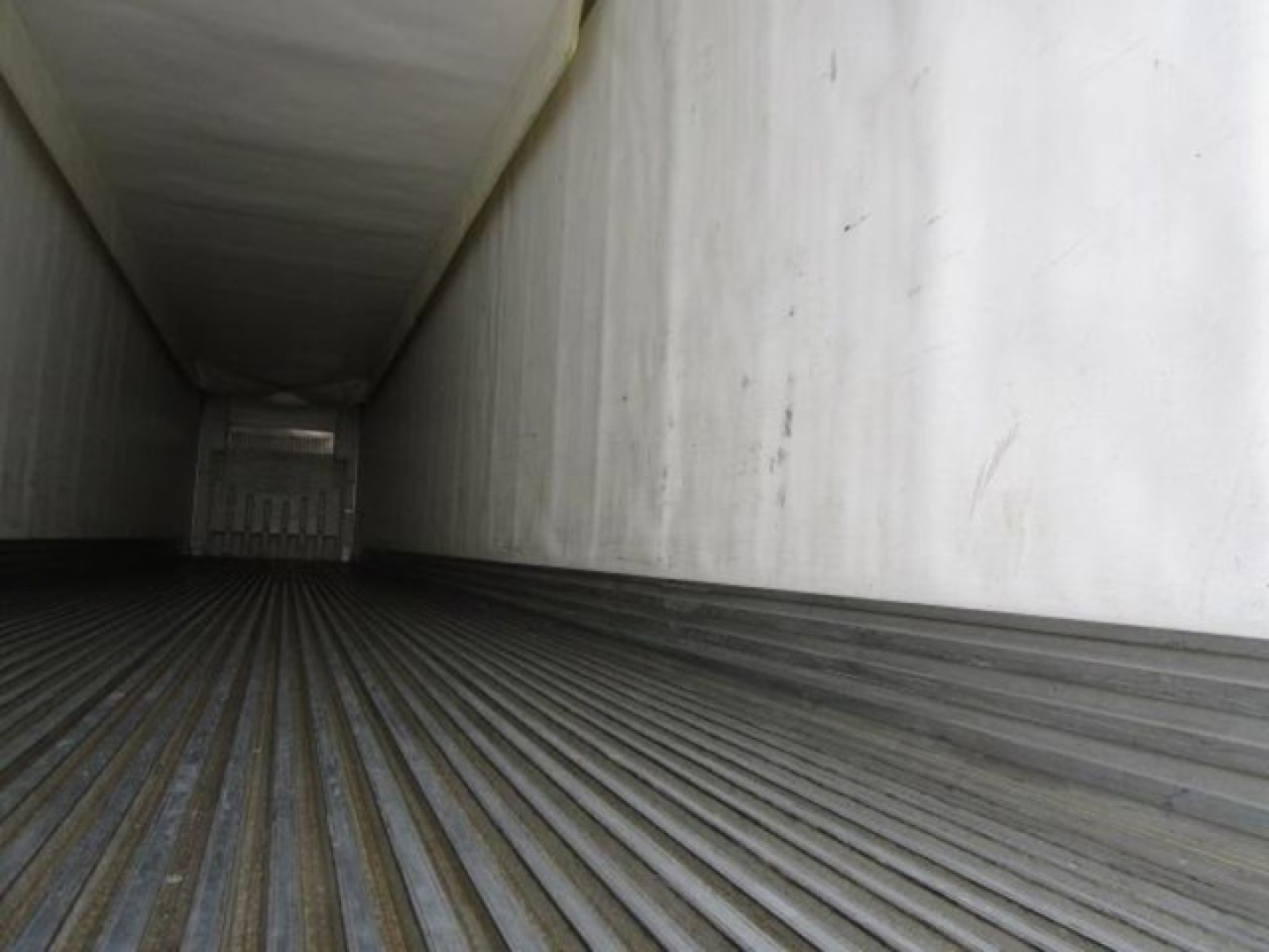 Trailer interior showing empty cargo area with ribbed floor and vertical walls in a refrigerated trailer.