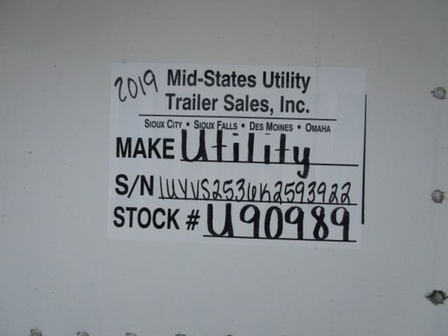 Label inside a trailer showing 2019 Mid-States Utility Trailer Sales, Inc. Make Utility, S/N UYVS2536K2593922, STOCK # U90989 with handwritten 2019 and stock number.