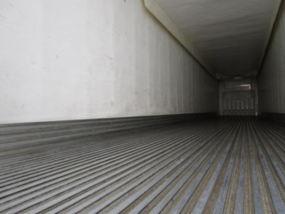 Interior of a refrigerated trailer showing ribbed metal floor and white side walls, empty cargo area.