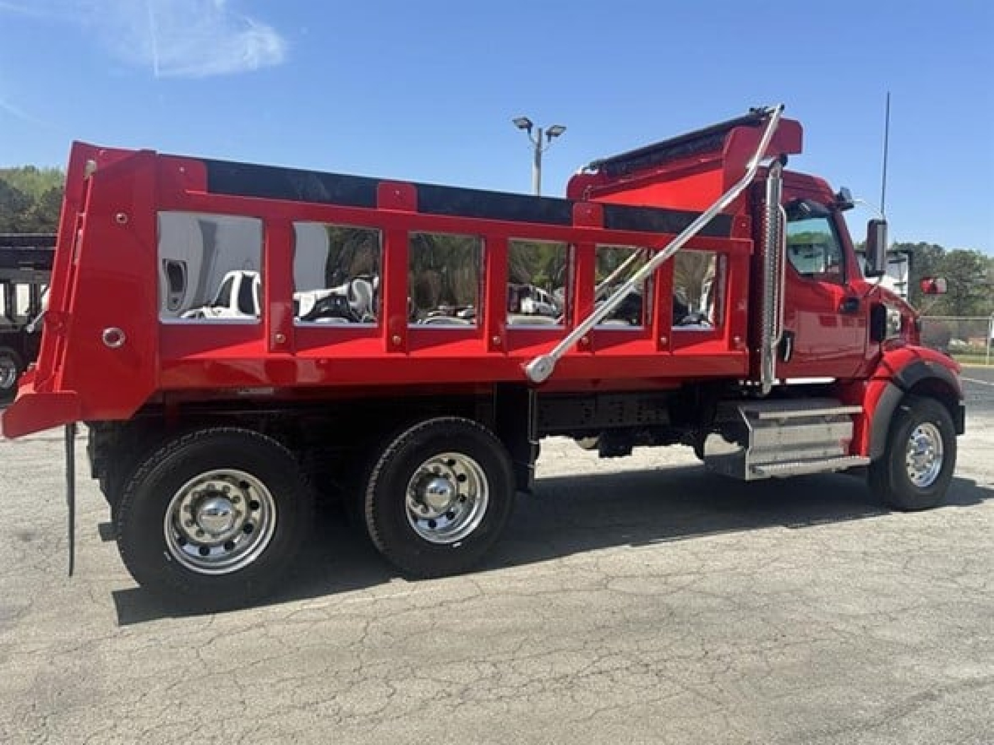 A red Western Star dump truck with a split-frame dump bed and chrome wheels, side view showing the cab and bed.