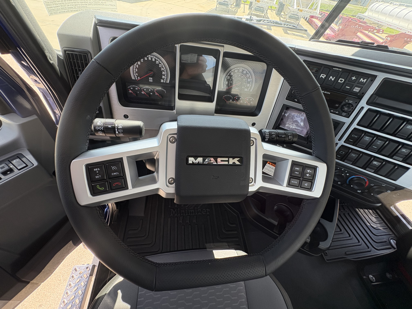 Mack PI64T steering wheel and dashboard with gauges and controls in truck cab interior.