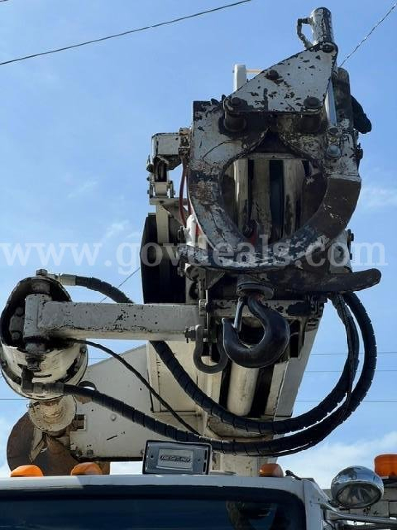 Front view of a digger-derrick attachment mounted on a Freightliner FL80 truck showing crane hook and hydraulic components.