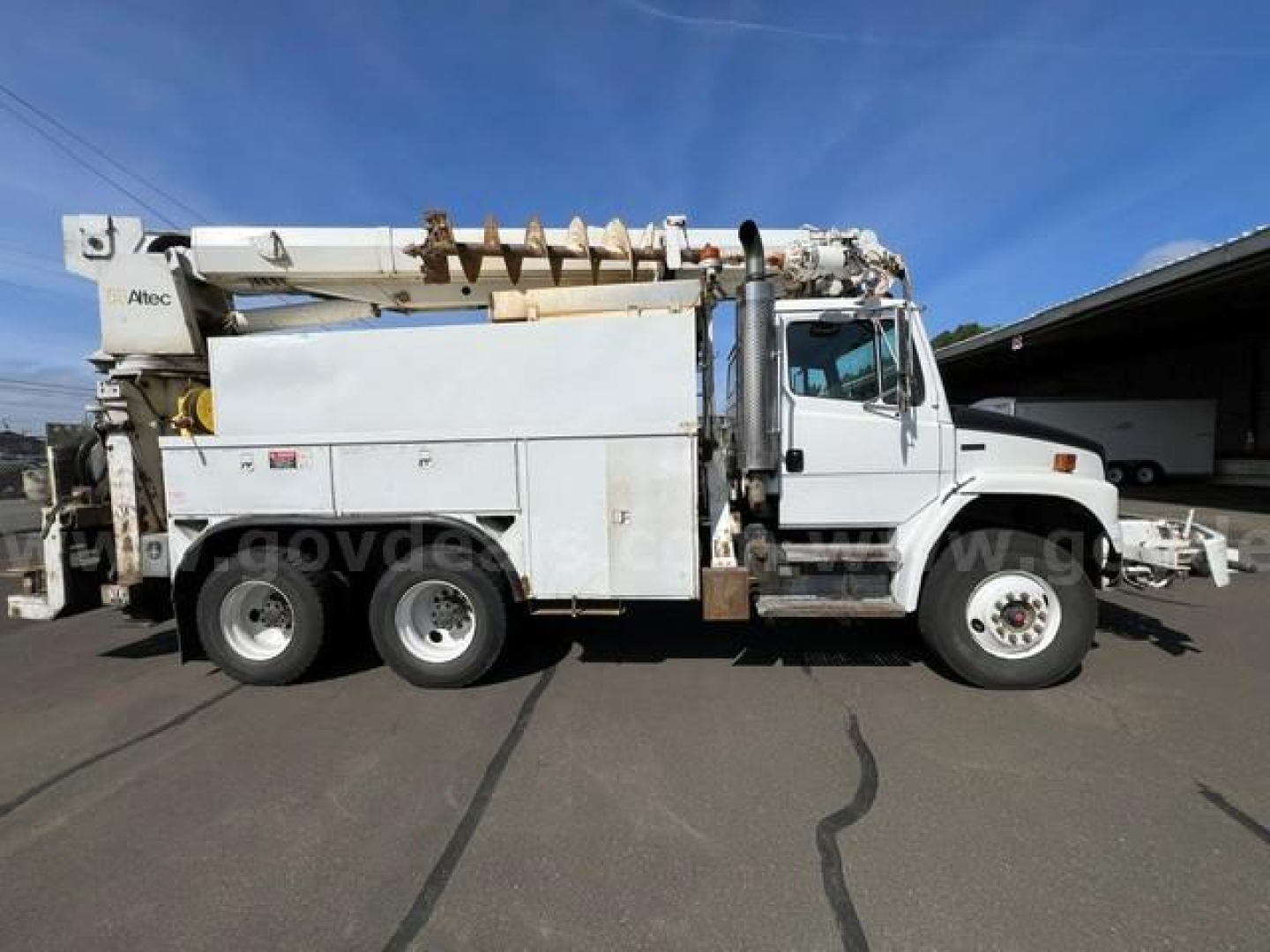 Digger-Derrick truck side view showing utility service body and mounted auger/rig on Freightliner FL80