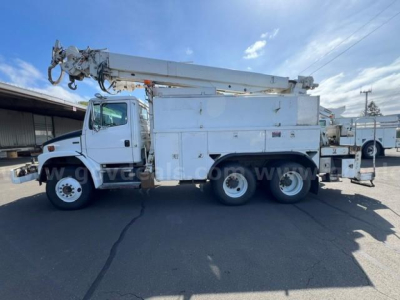 Truck side view of a white Freightliner FL80 utility/service body with a mounted boom crane and storage compartments. No visible labels readable.