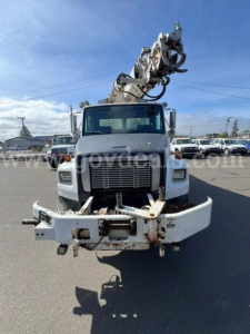 Truck front view of a 1999 Freightliner FL80 with a mounted boom crane, large front bumper, grille, and mirrors visible.