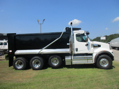 Dump truck with white cab and black dump body showing heavy-duty wheels and chrome step, side view.