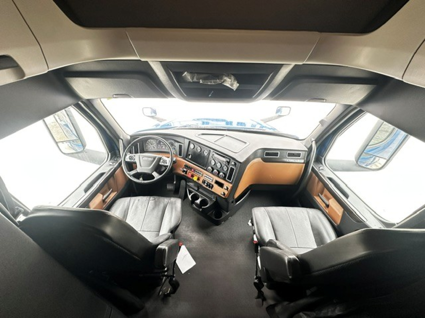 Cab interior of 2022 Freightliner Cascadia 126 truck showing the dash, steering wheel, and two front seats; windshield and overhead storage visible.