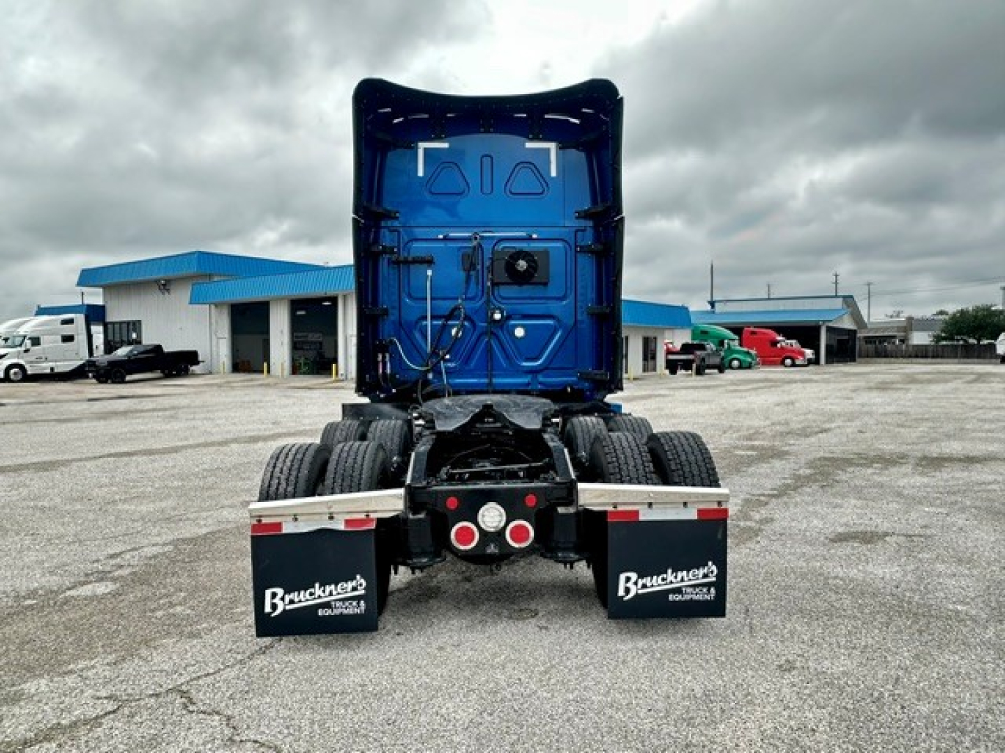 Rear view of a blue Freightliner Cascadia 126 tractor-trailer without trailer, showing rear bumper, mud flaps with Bruckner's logo, and dual rear axles.
