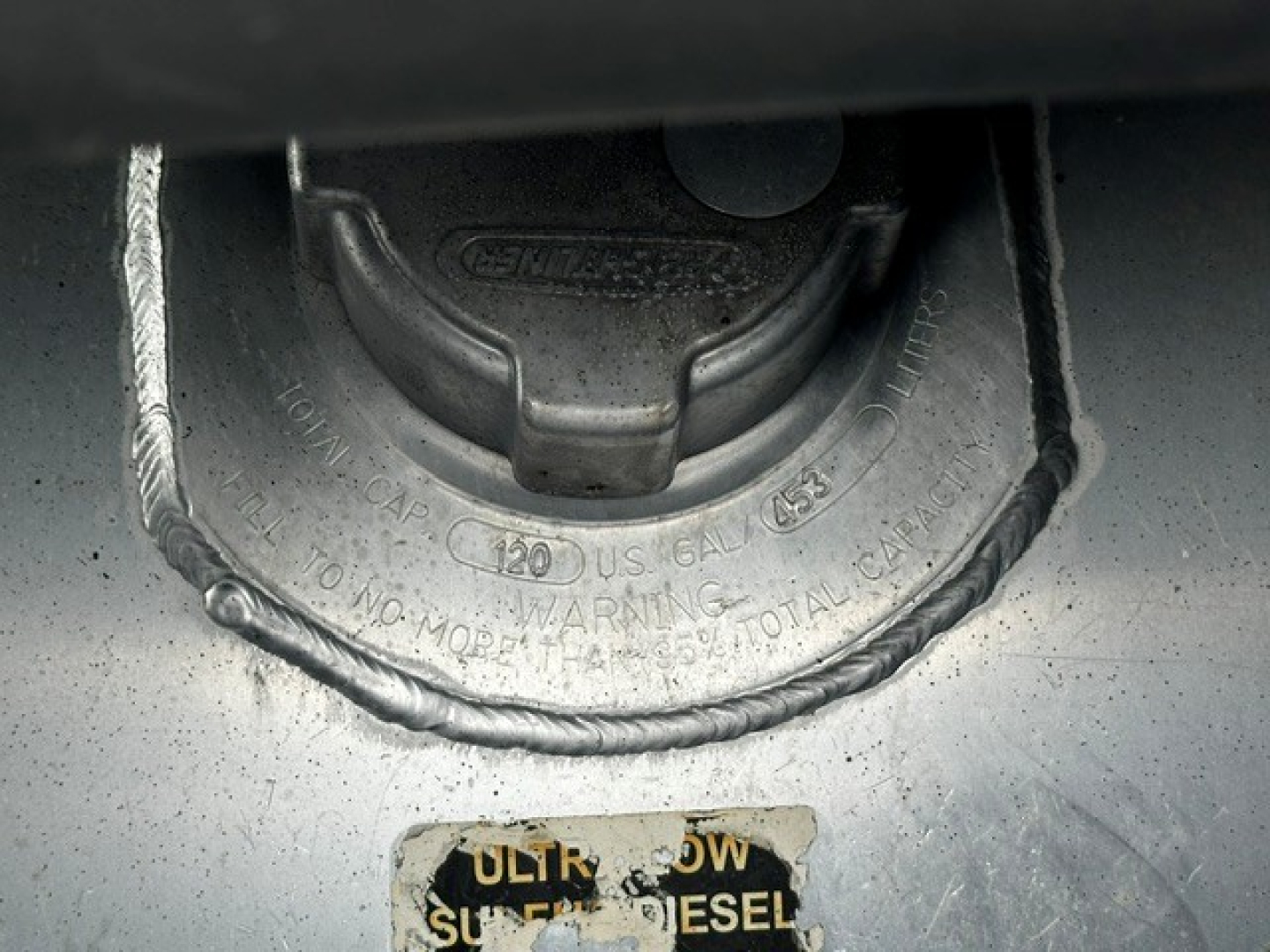 Diesel fuel cap area on Freightliner CASCADIA, showing fuel cap housing with chained cap and warning ring around the cap.
