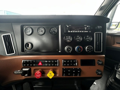 Dashboard of a 2022 Freightliner Cascadia 126 showing gauges, switches, and HVAC controls in orange-brown dash area.