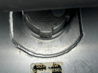 Diesel fuel cap area on Freightliner CASCADIA, showing fuel cap housing with chained cap and warning ring around the cap.