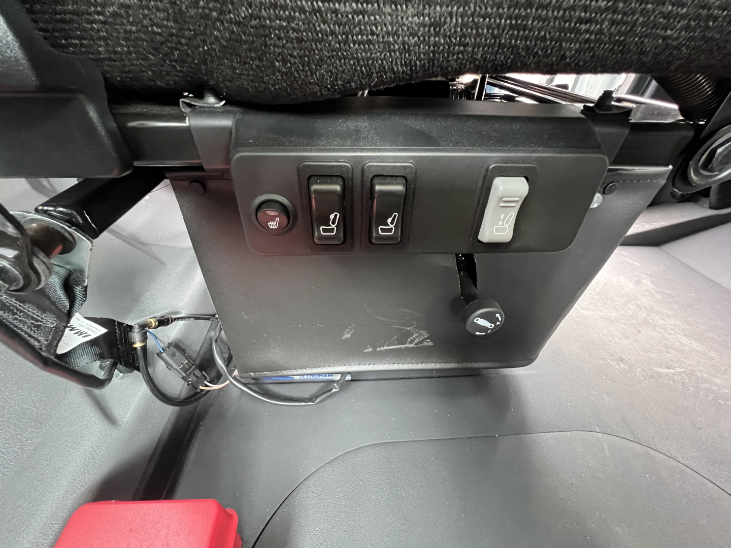Mack GR64B interior panel showing switches and wiring under dashboard. Visible labels: three black switches with icons, one light gray switch, small circular port, surrounding panel with texture.