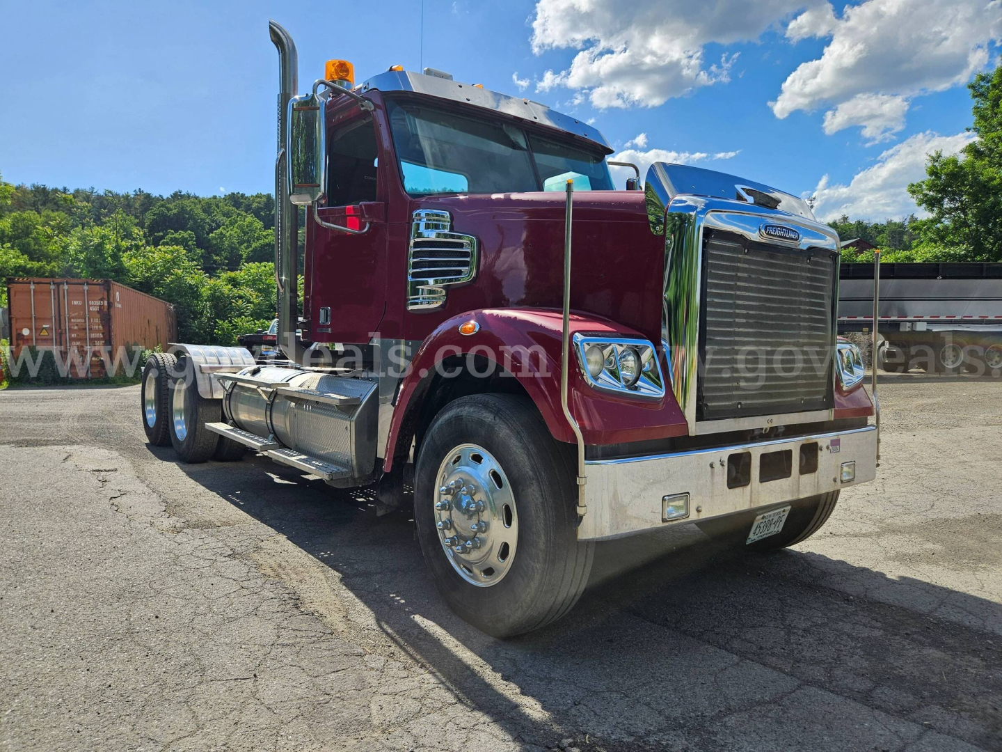 Truck front-left view showing 2014 Freightliner Coronado SD with maroon cab and chrome grille, diesel engine bay, dual rear axles, and chrome bumper.