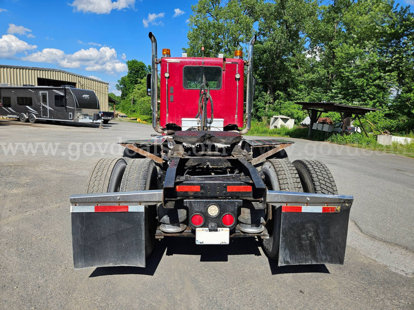 Rear view of a red 2014 Freightliner Coronado SD truck chassis showing dual rear axles, mud flaps, and taillights.