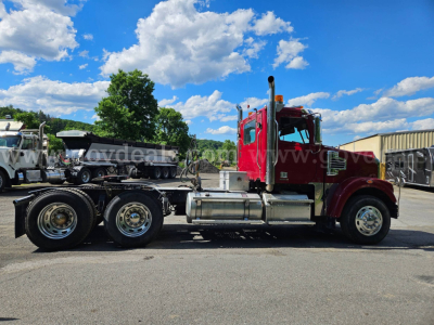 Truck side view of a 2014 Freightliner Coronado SD with red cab and dual rear axles in a lot.