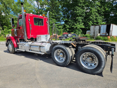 Freightliner Coronado SD truck cab with red exterior and dual rear axles, side profile view, chrome fuel tanks, and fifth wheel hitch area.