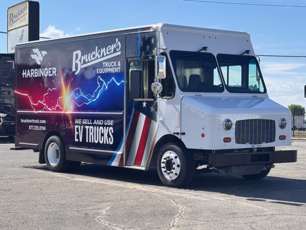Truck side view showing Harbinger S655 graphics with Brackner's Truck & Equipment EV Trucks branding on a colorful wrap; cab appears silver with chrome grille.
