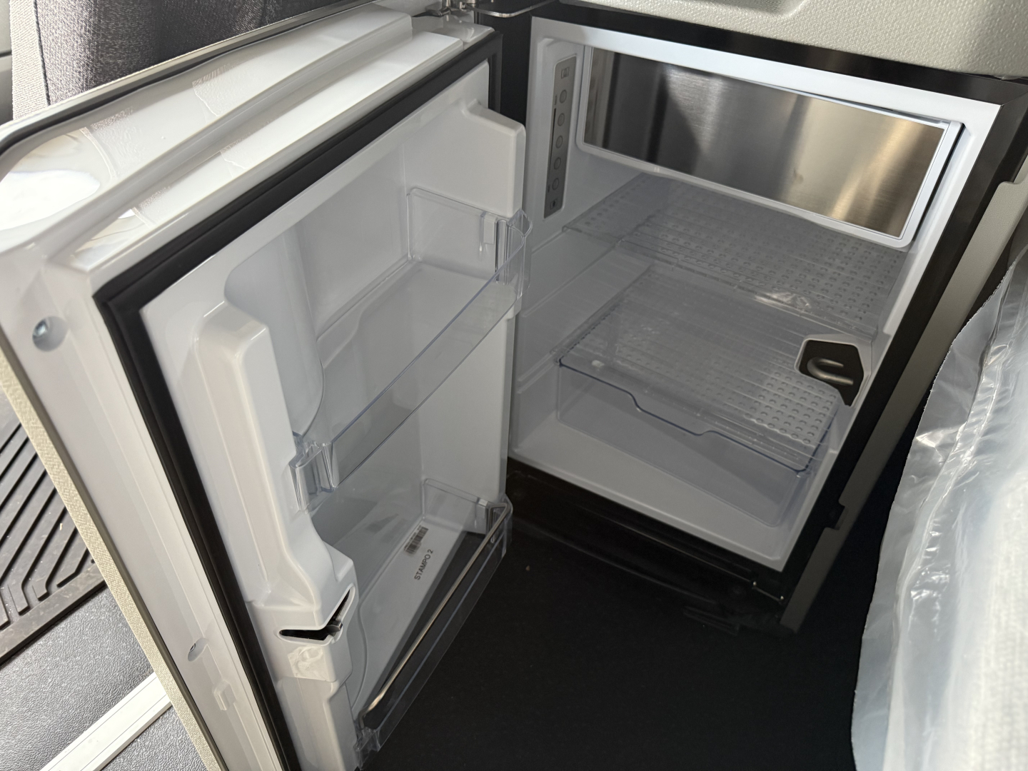 Volvo VNL64T840 cab fridge and empty freezer in deluxe sleeper interior showing small fridge with open door and empty shelves.