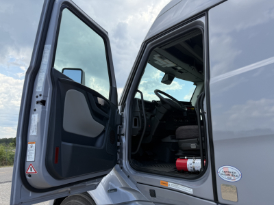 Volvo VNL64T840 cab interior with open driver door showing steering wheel and dashboard.