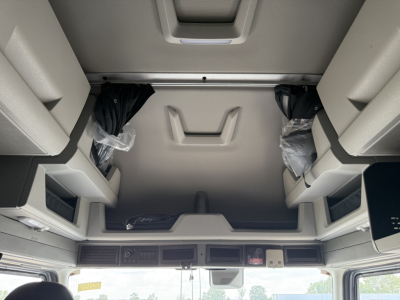 Volvo VNL64T840 truck cab interior overhead storage area with sunroof window and sun visor, showing hanging parts in plastic bags and overhead console