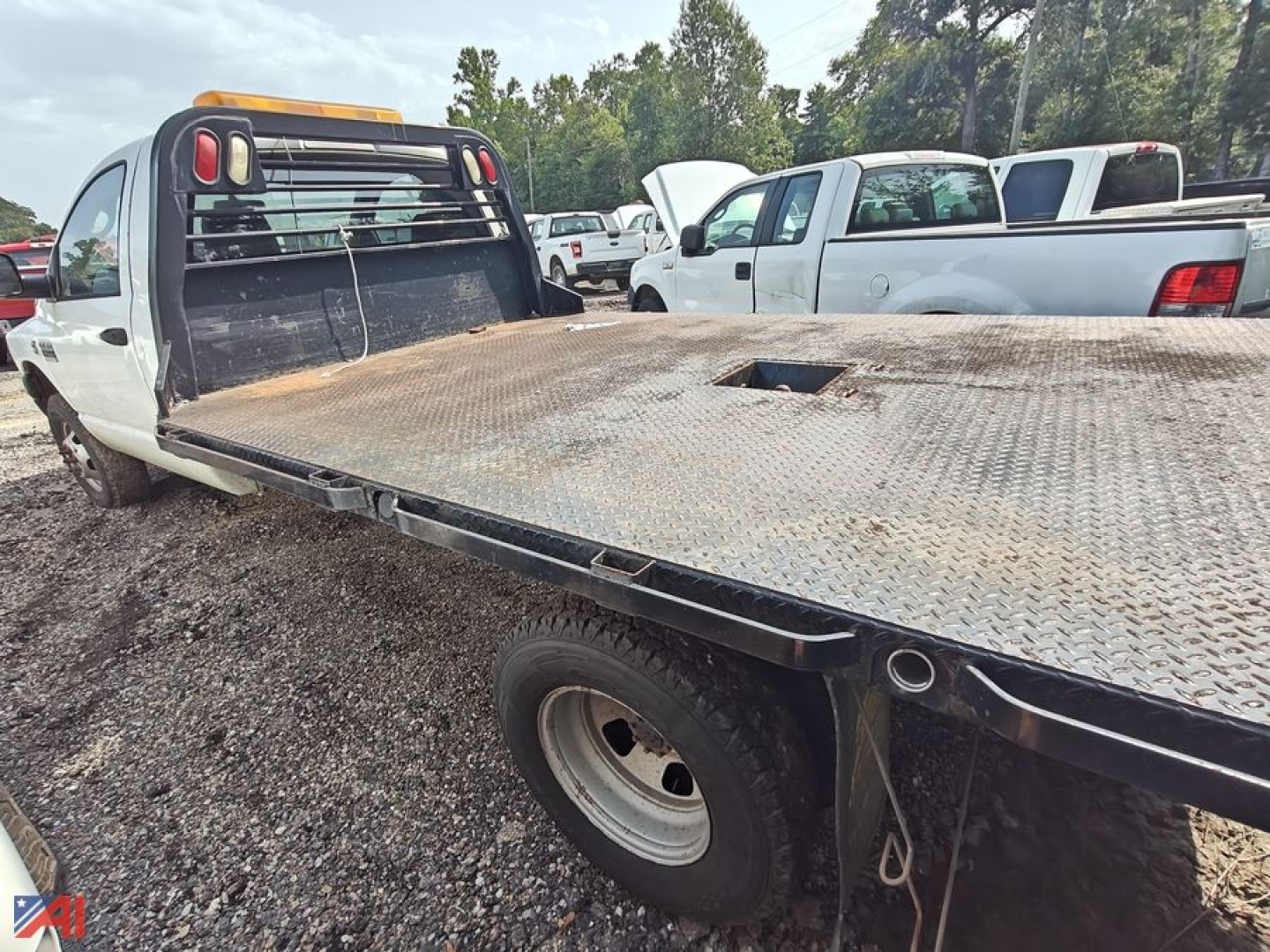 Flatbed truck bed with diamond plate steel surface and rear cab backrest on a 2008 Dodge Ram 3500 flatbed pickup in a used vehicle lot.