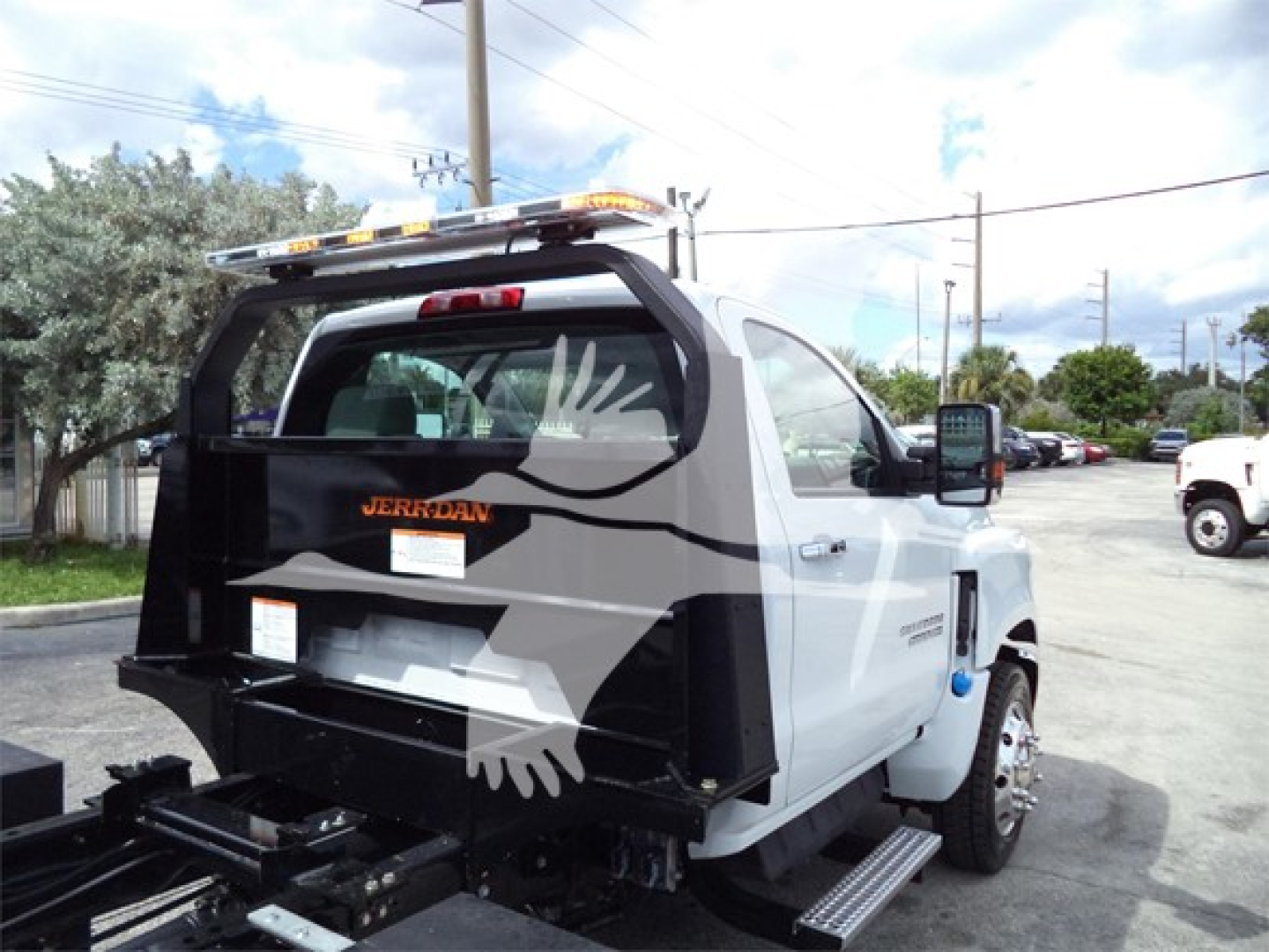 Truck rear view showing rollback bed with lettering and a graphic; Silverado 6500HD badge and rear bumper setup visible.