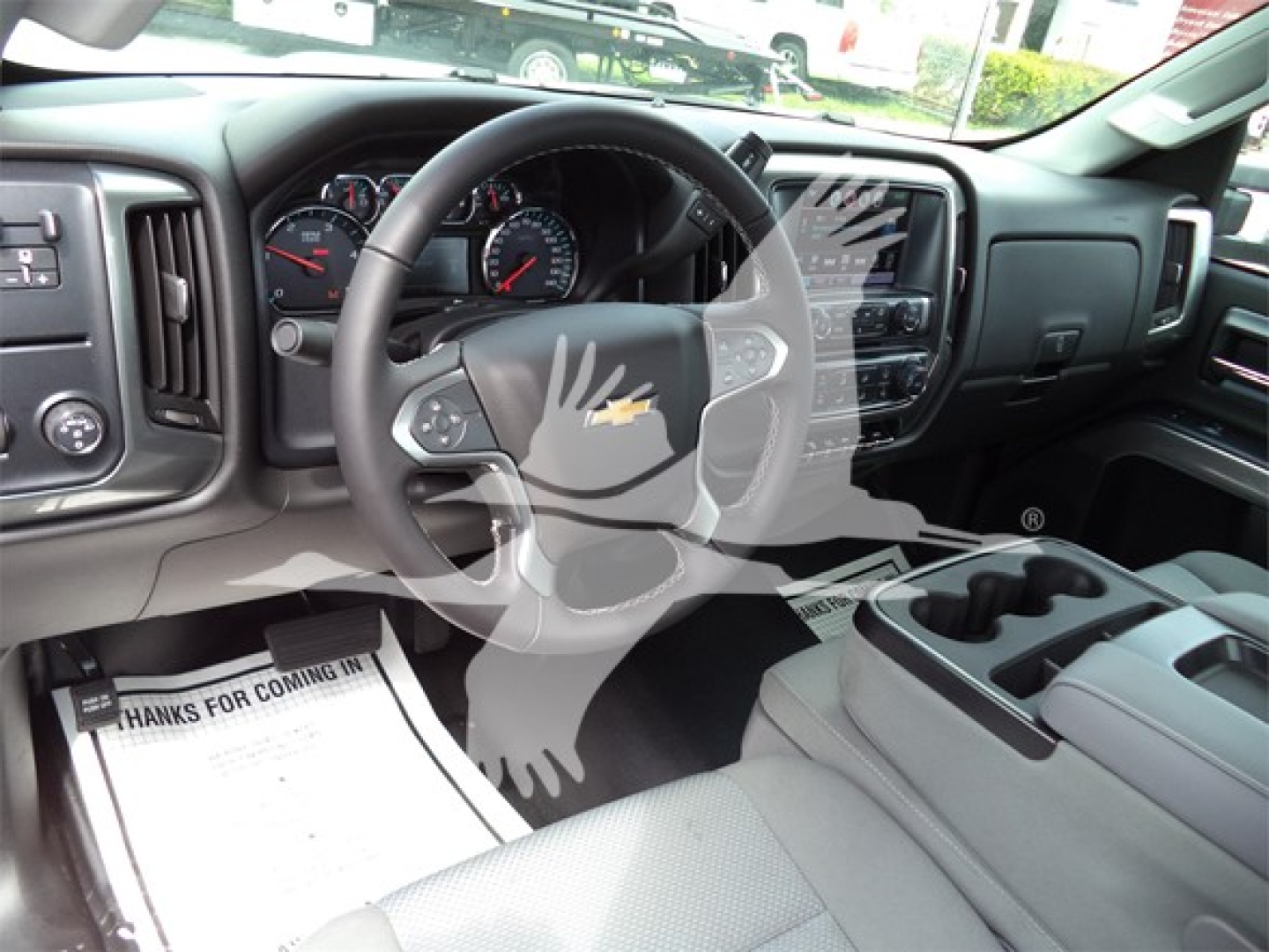 Inside view of a Chevrolet Silverado 6500HD truck cab showing steering wheel, dashboard, and center console. Visible text includes 'Chevrolet' emblem on steering wheel and vehicle controls.